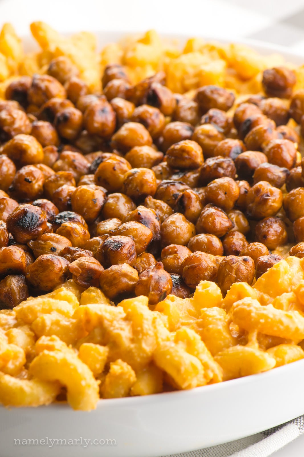 Looking a smoky roasted chickpeas in a bowl surrounded by vegan mac and cheese.