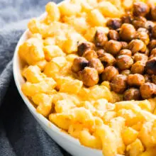 Closeup of Vegan Stovetop Mac and Cheese with Smoky Chickpeas in a white bowl next to a blue kitchen towel
