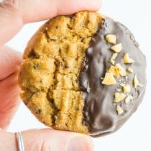 A single chocolate-dipped peanut butter cookie is held between two fingers, ready to be eaten!