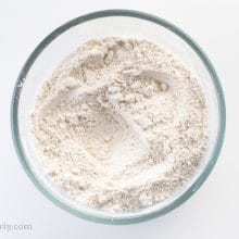 Dry ingredients, like flour, in a glass bowl.