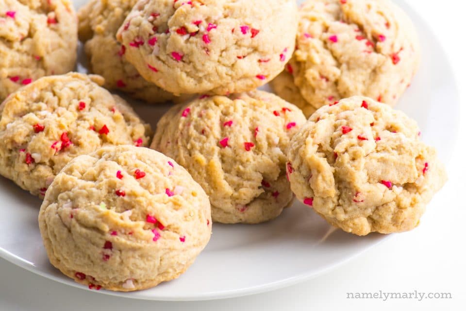 A white plate is full of valentines cookies with little red, white, and pink sprinkle hearts.
