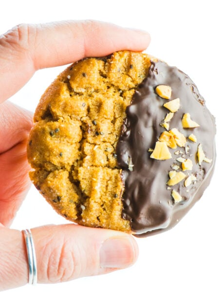 A single chocolate-dipped peanut butter cookie is held between two fingers, ready to be eaten!