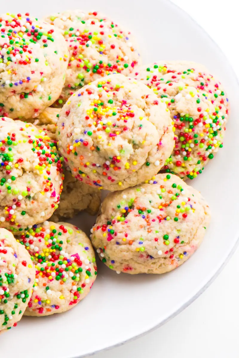 A white plate has several colorful confetti cookies, sugar cookies with sprinkles baked right into the dough.