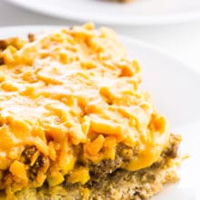A slice of vegan breakfast casserole sits on a plate with another slice behind it.