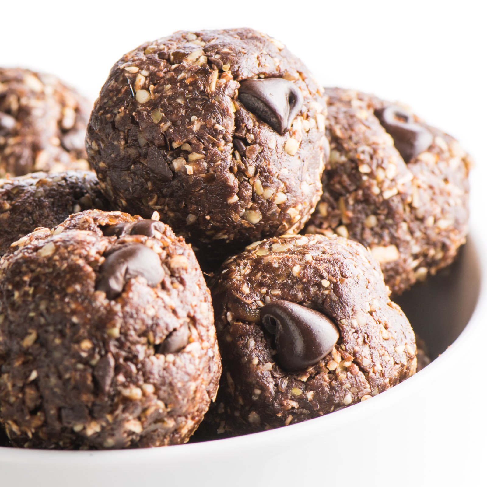 A close-up of chocolate no bake energy balls in a white bowl.