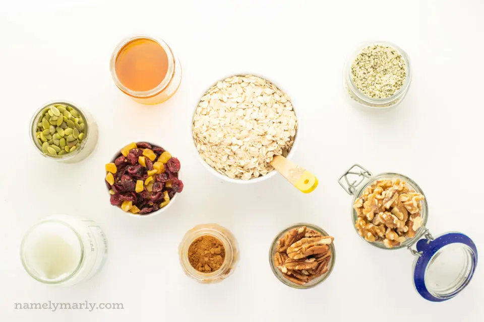 Several bowls of ingredients for granola on a white counter.