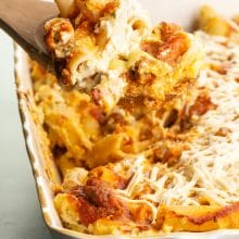 A spatula holds meatless baked ziti over the rest of the casserole dish.