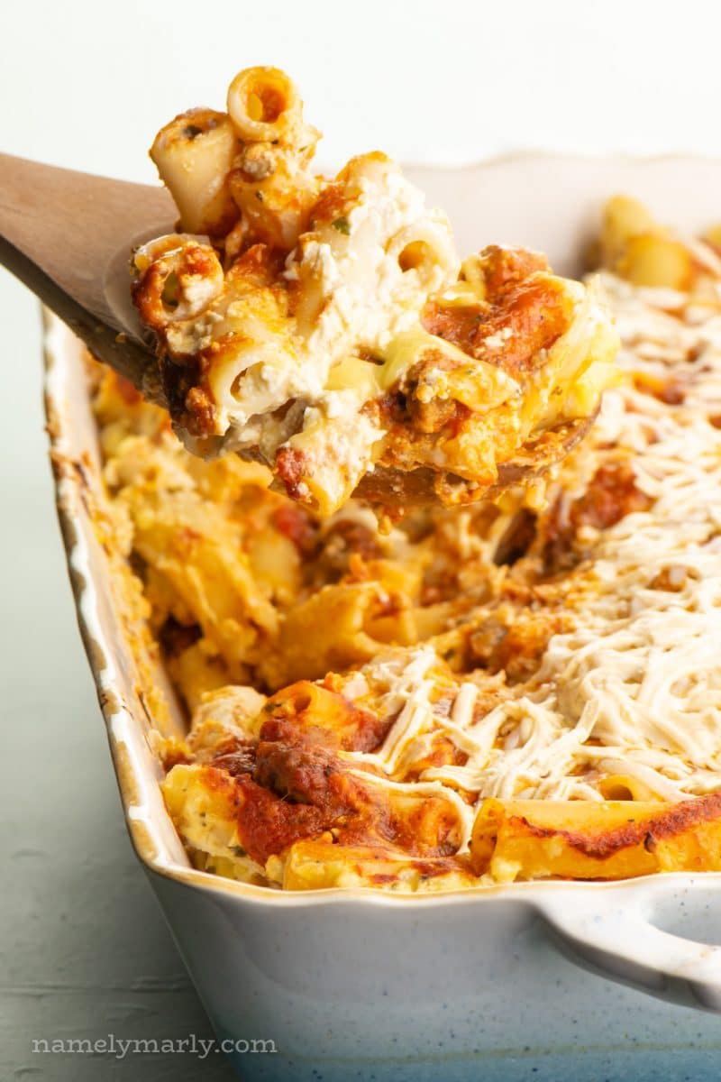 A spatula holds meatless baked ziti over the rest of the casserole dish.