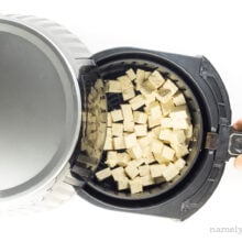 Tofu cubes are in an air fryer basket.