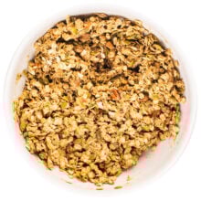 A large white bowl full of granola ingredients covered in sauce.