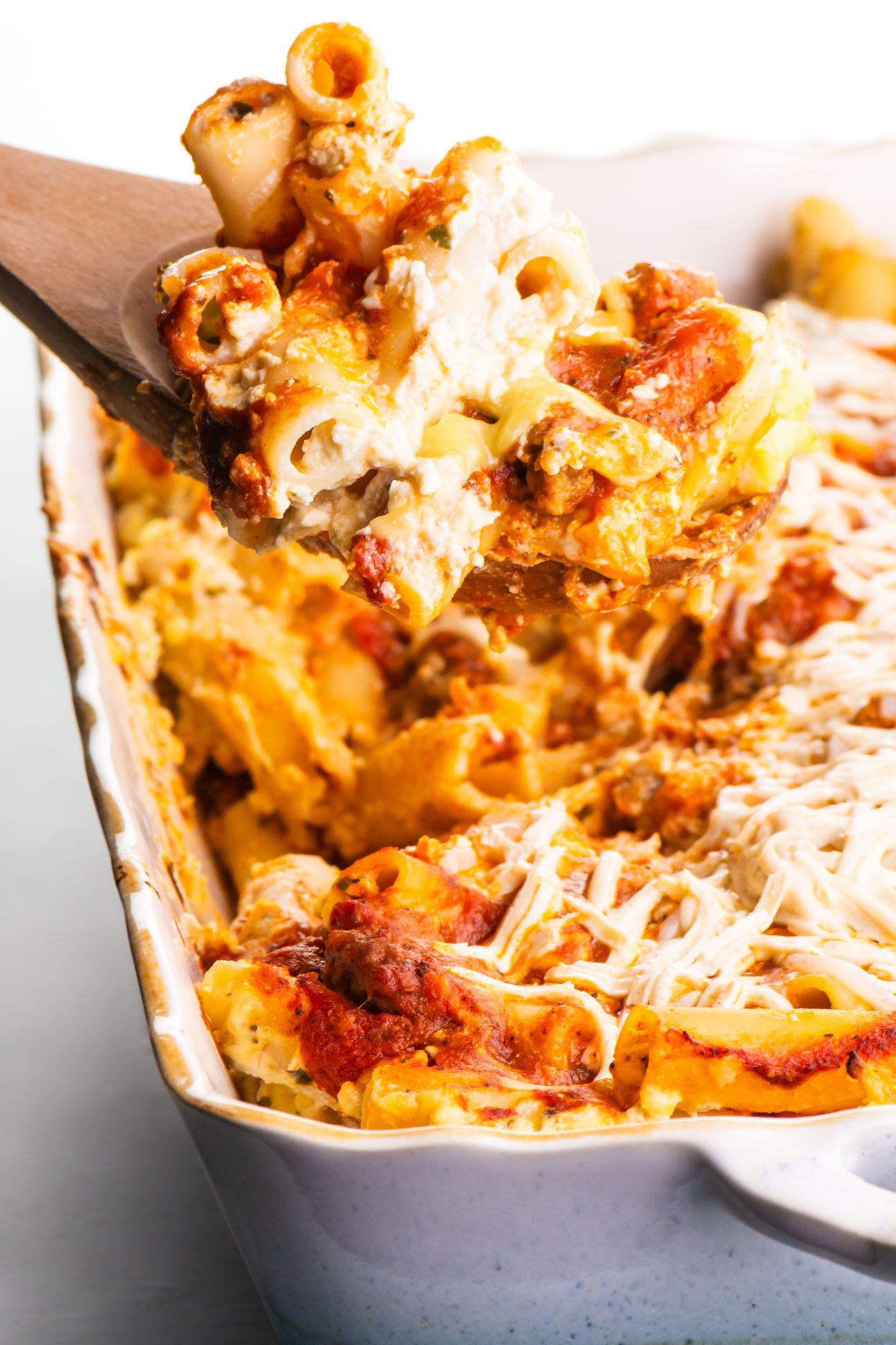 A spatula holds meatless baked ziti over the rest of the casserole dish.