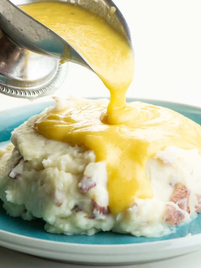 Vegan gravy is poured over a big plate of mashed potatoes.