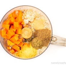 Ingredients like sweet potatoes and ground flax seeds are in a food processor bowl.