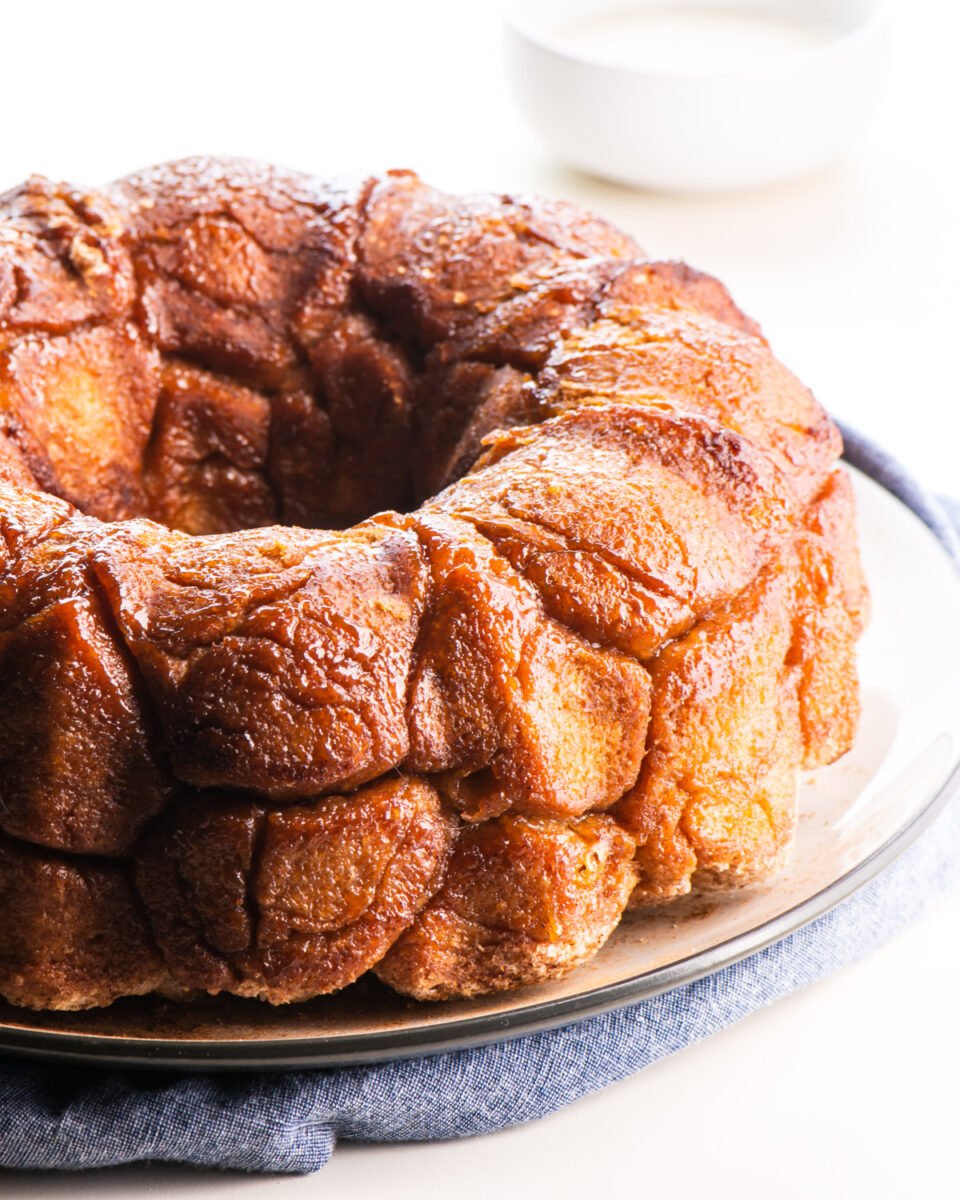 A loaf of pull-apart bread sits on a plate. There is frosting in the background.