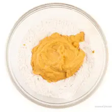 A sweet potato mixture has been added to a bowl with flour in it.