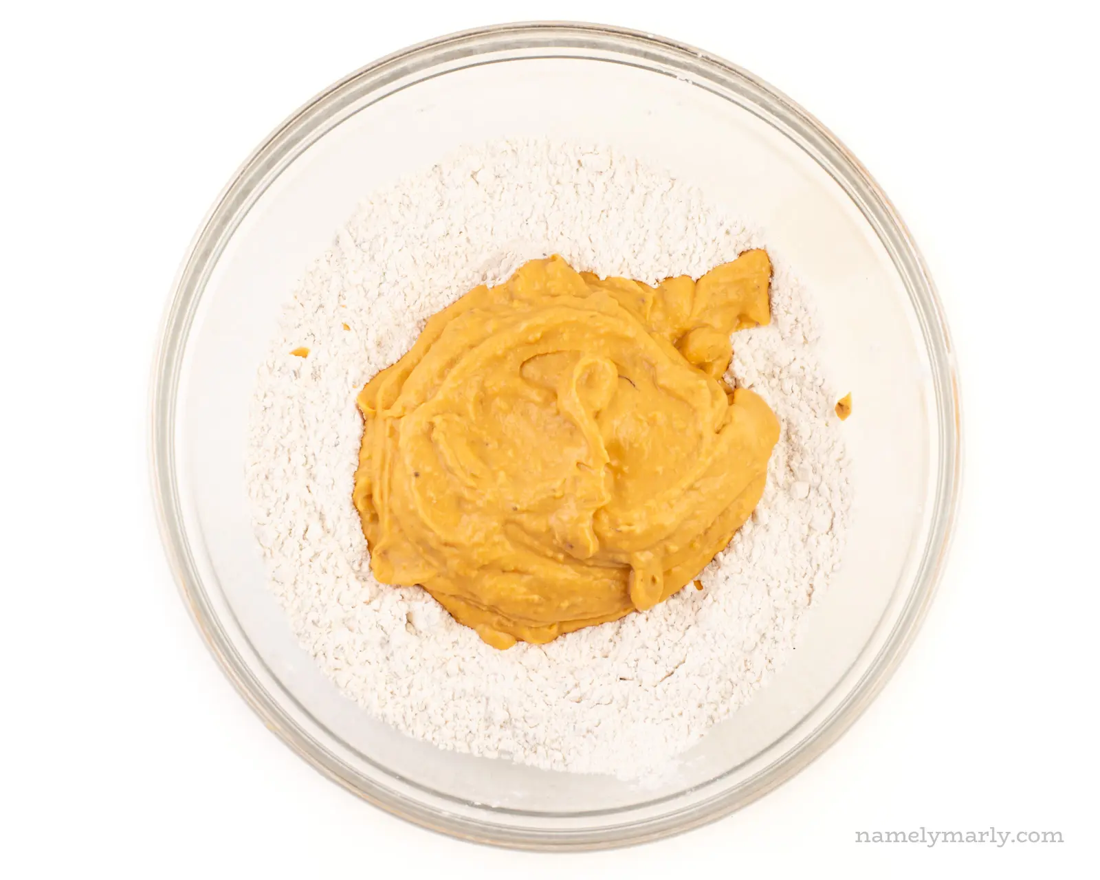 The sweet potato mash has been added to the flour mixture in a large, glass bowl.