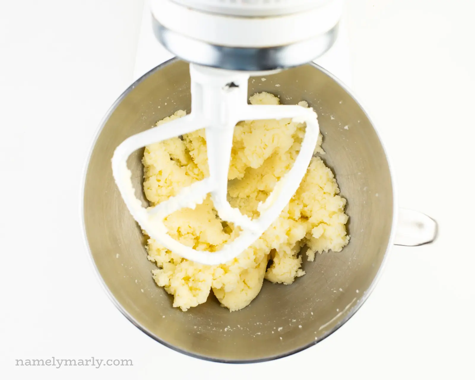 Looking down on a stand mixer to the creamed vegan butter and sugar in a mixing bowl.