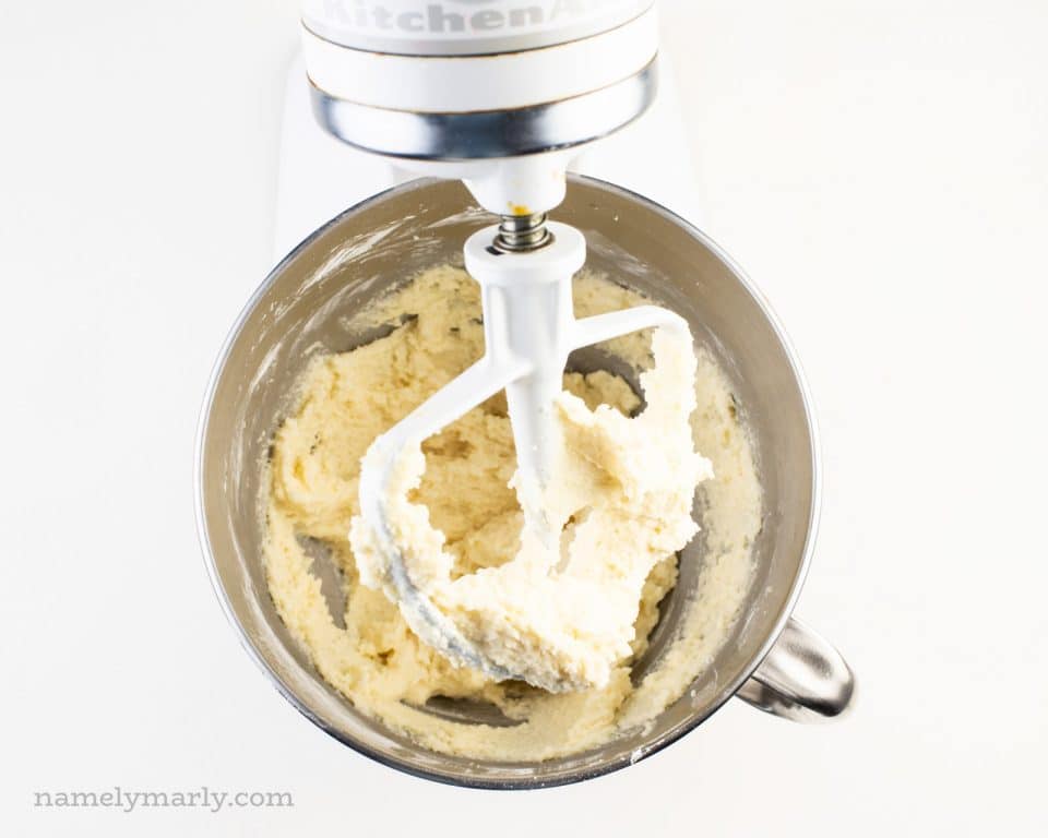 Looking down on a stand mixer with cake batter on the beaters and in the mixing bowl.