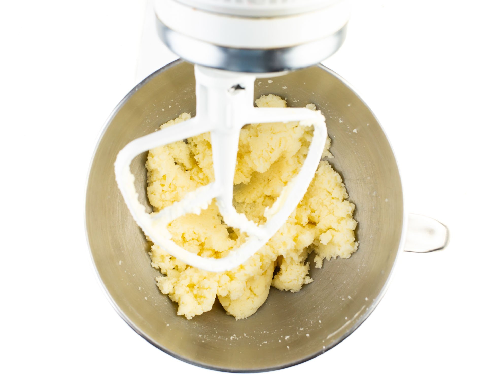 Looking down on a stand mixer to the creamed vegan butter and sugar in a mixing bowl.