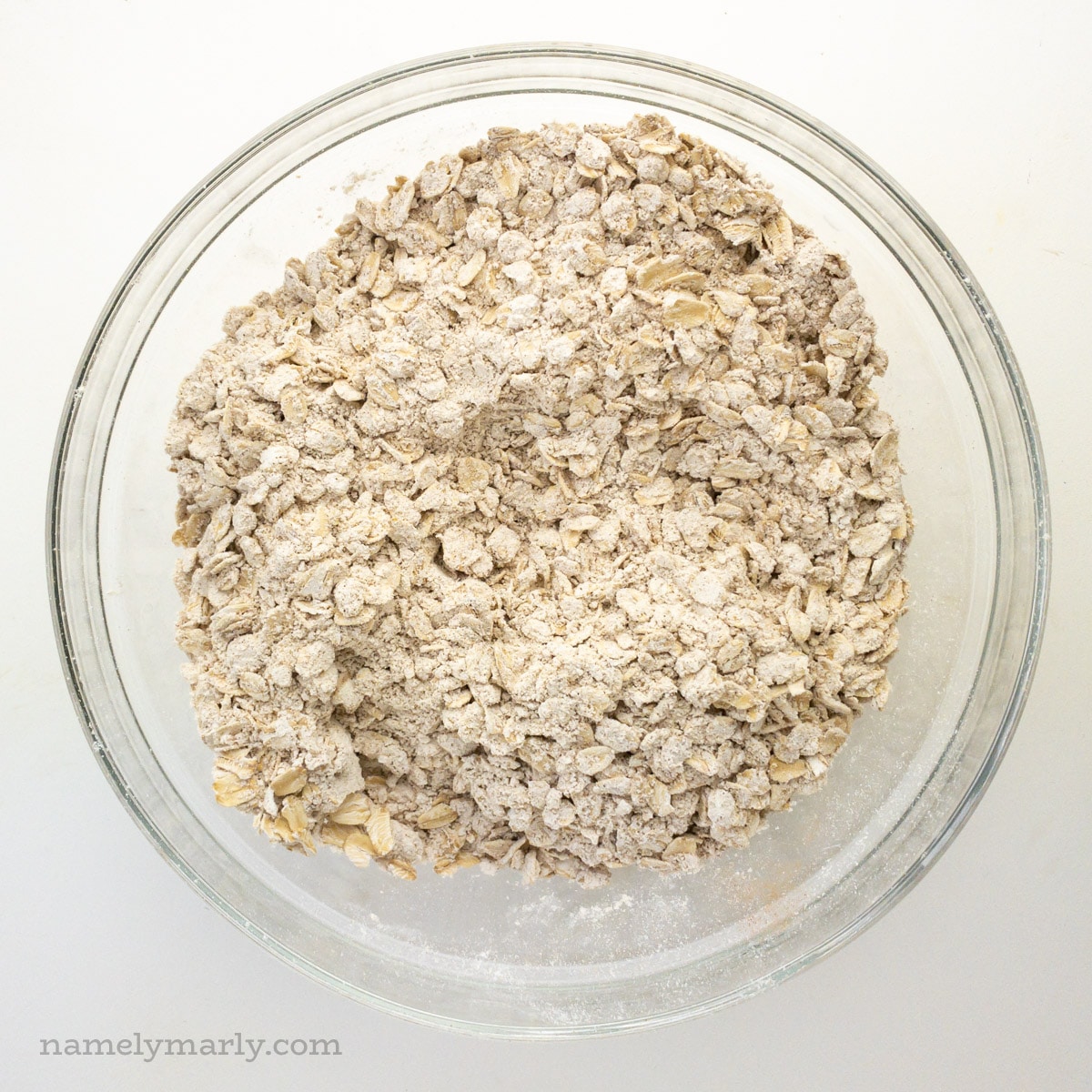 A glass bowl holds flour and oatmeal mixture for cookies.