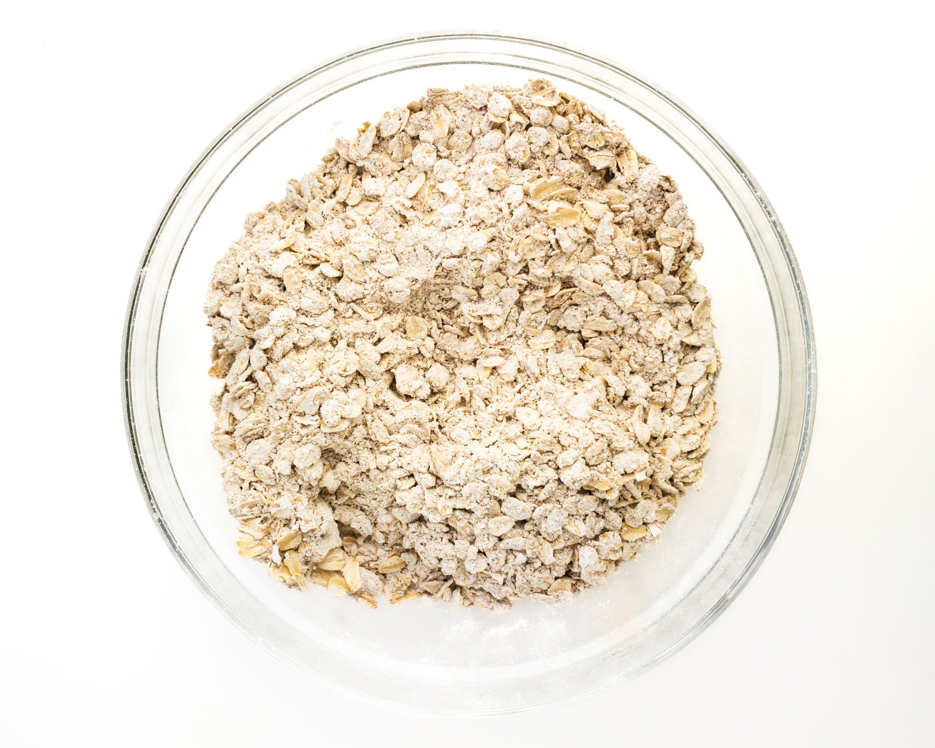A glass bowl holds flour and oatmeal mixture for cookies.