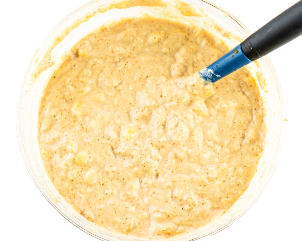 Vegan banana muffins batter in a bowl with a blue spatula.