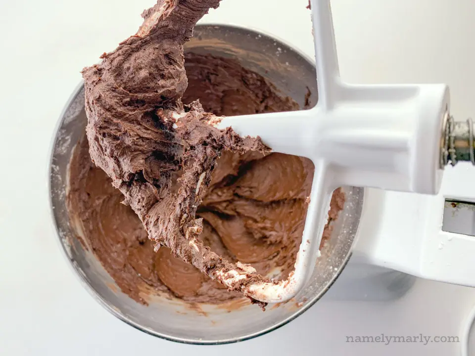 Looking down on a stand mixer with creamy chocolate frosting.