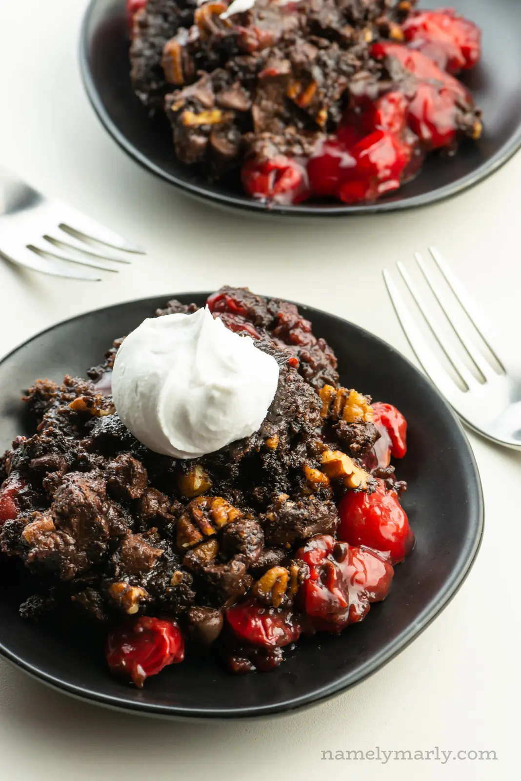 Looking down on two plates with chocolate cherry dump cake and forks between them.