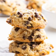 A stack of three cookies sits in front of a baking rack with more vegan cookies.