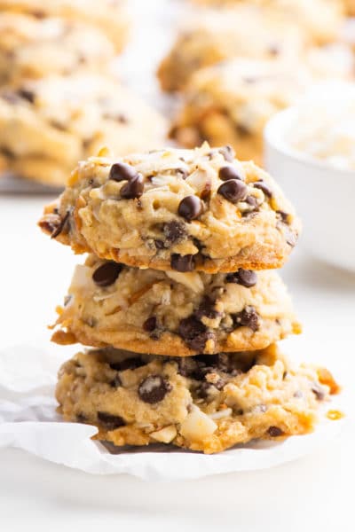 A stack of three cookies sits in front of a baking rack with more vegan cookies.
