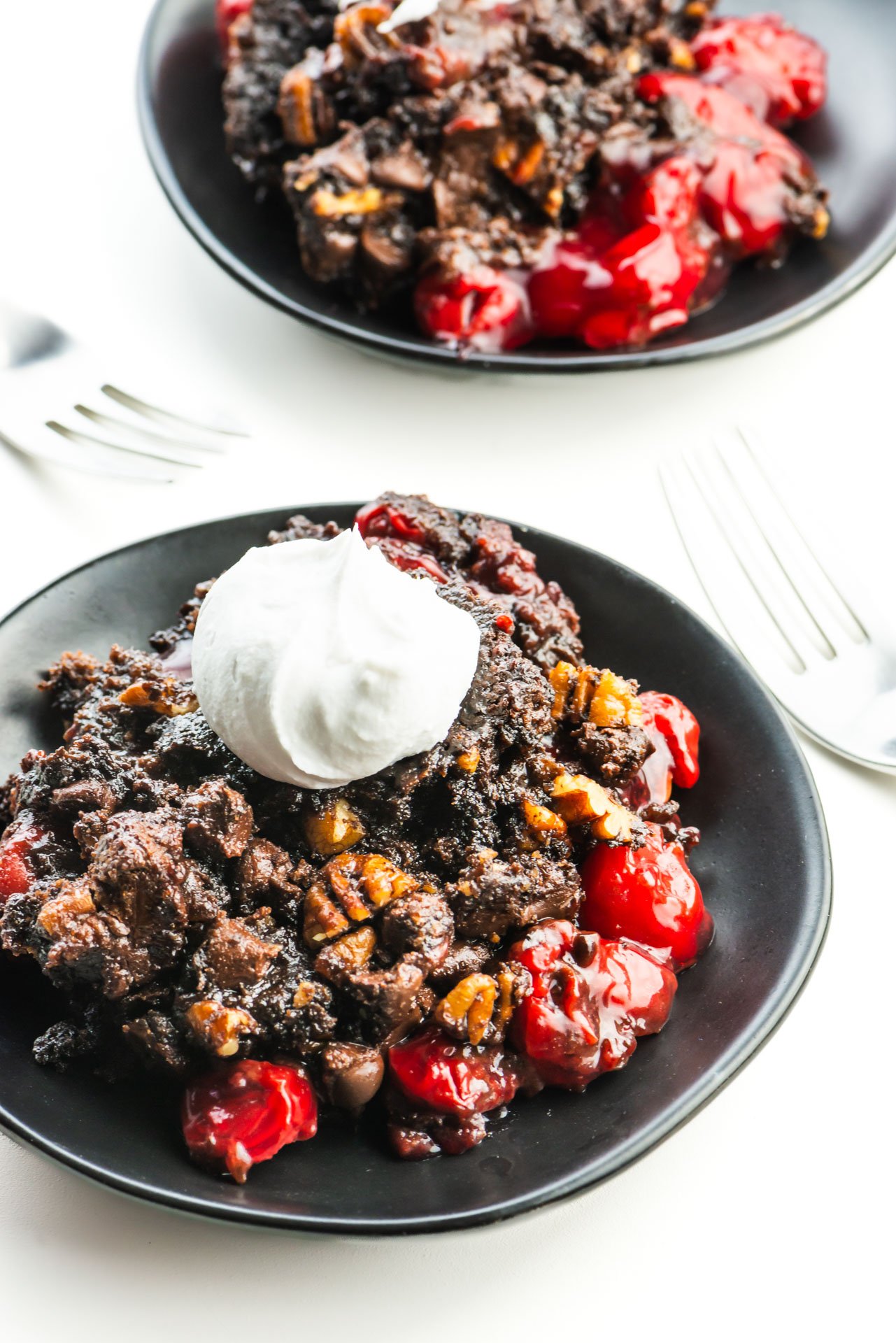 Looking down on two plates with chocolate cherry dump cake and forks between them.