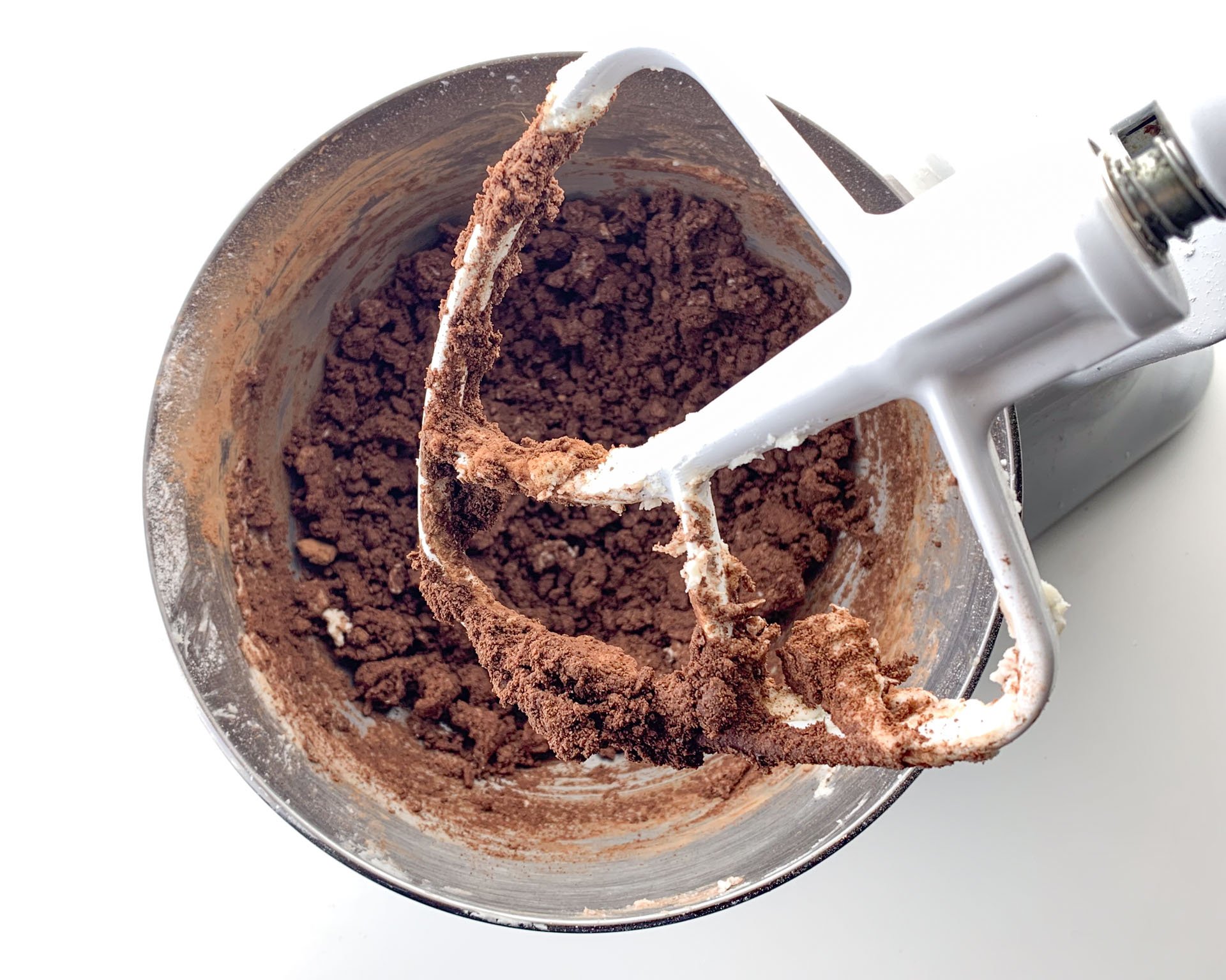 Looking down on a stand mixer with cocoa powder added to creamed butter and sugar.
