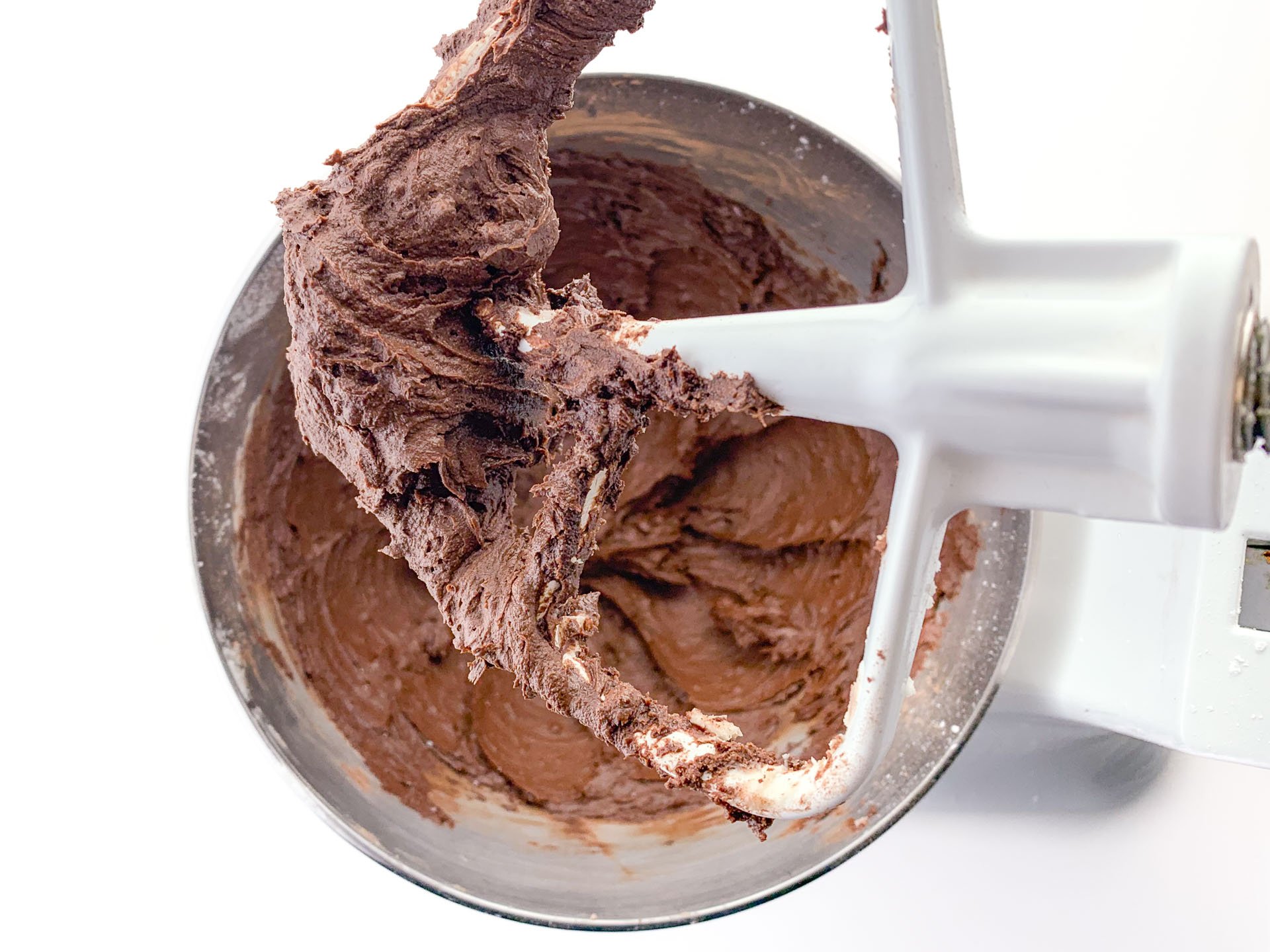 Looking down on a stand mixer with creamy chocolate frosting.