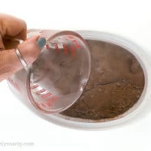 A hand pours hot water over chocolate cake batter.