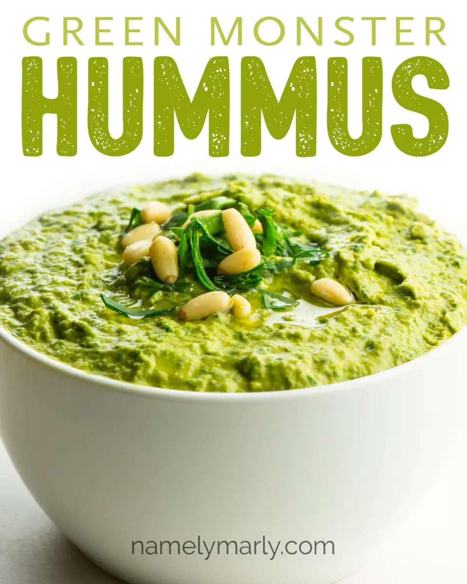 An image of green hummus in a bowl topped with chopped greens and pine nuts. The text above it reads: Green Monster Hummus.