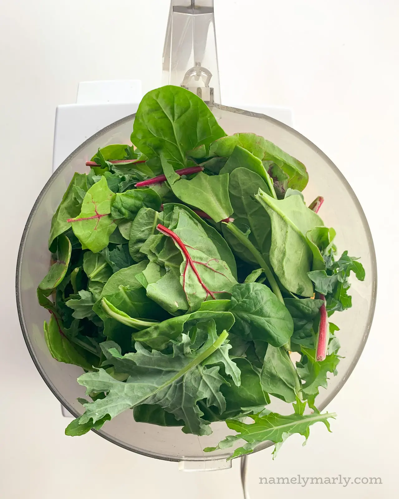 Power greens and other ingredients are in a food processor.