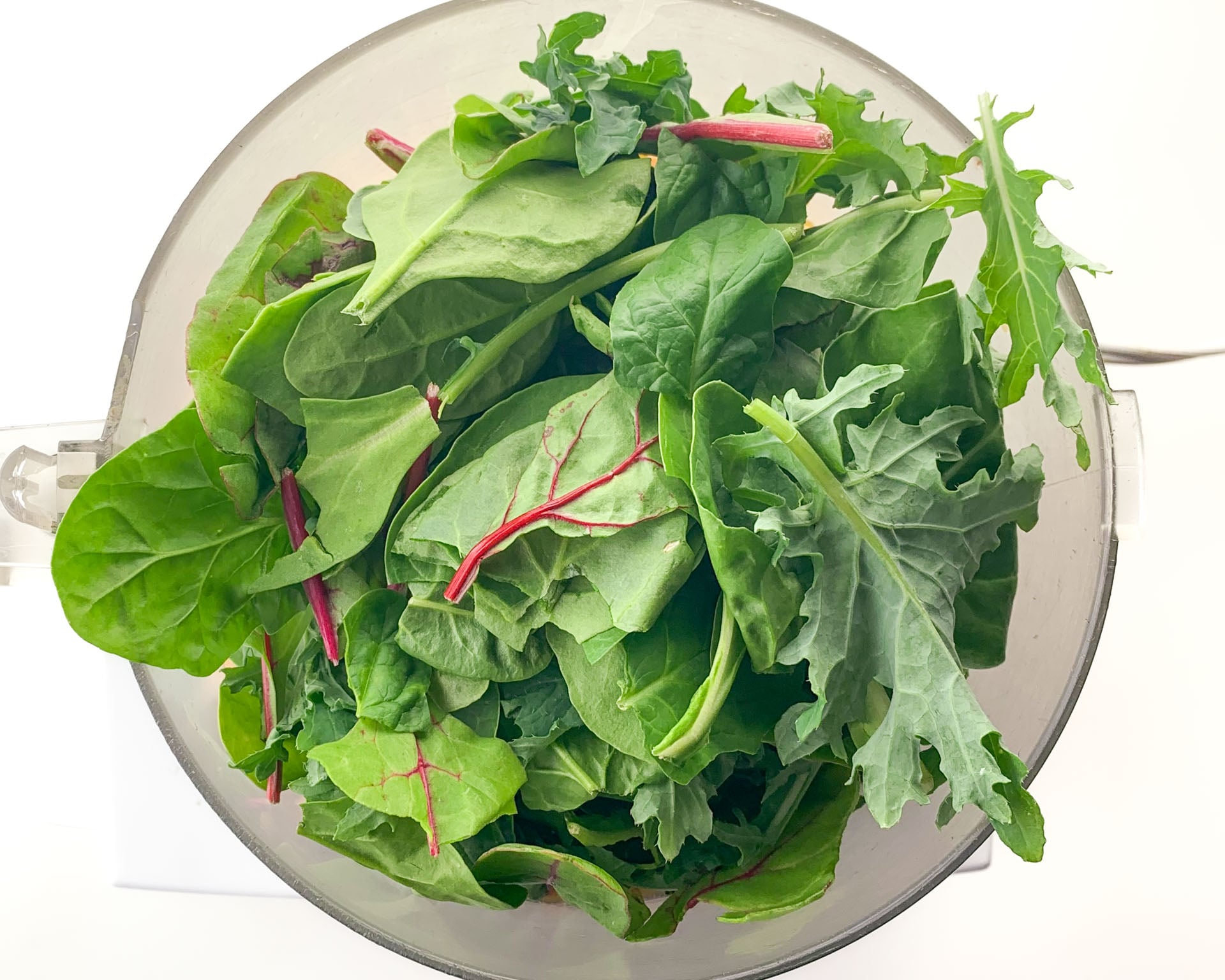 Power greens and other ingredients are in a food processor.
