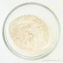 A flour mixture is in a glass bowl.