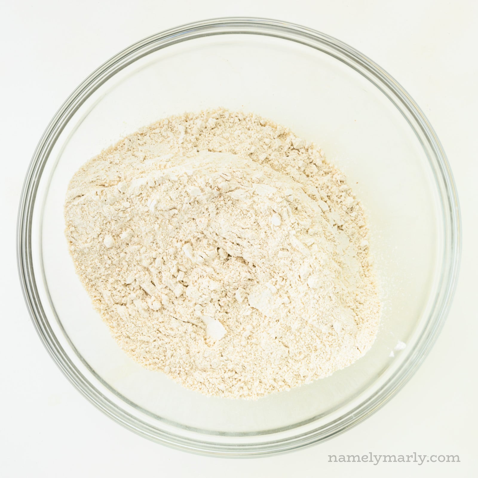 A flour mixture is in a glass bowl.