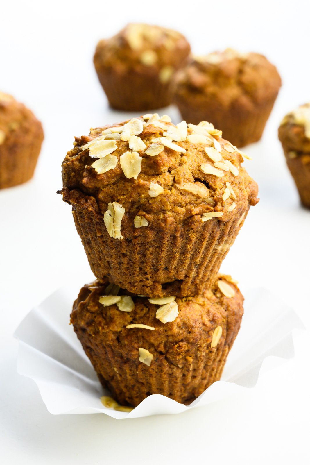 Two applesauce muffins are stacked on top of each other with more muffins behind them.