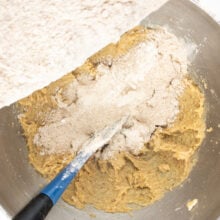 The dry ingredients are being poured into a mixing bowl with the butter sugar mixture.