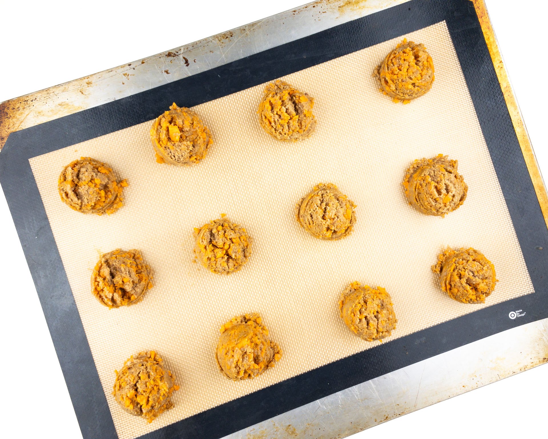 A cookie sheet lined is full of rows of unbaked cookies.
