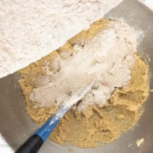 The dry ingredients are being poured into a mixing bowl with the butter sugar mixture.