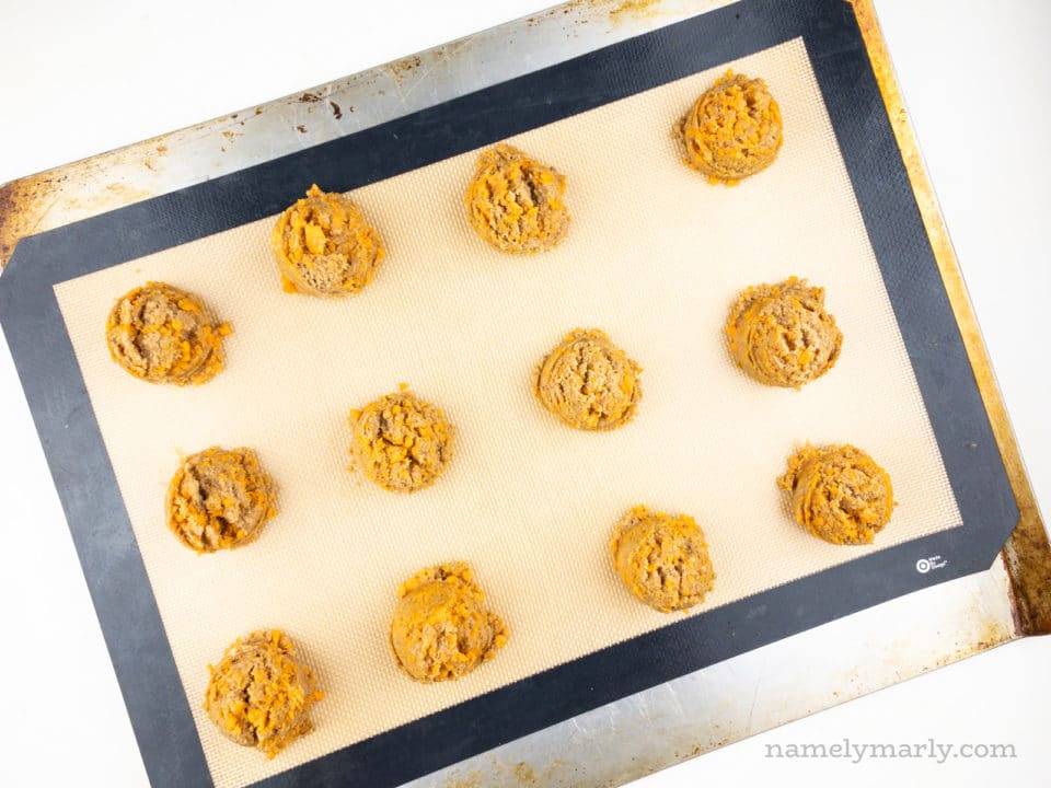 A cookie sheet lined is full of rows of unbaked cookies.