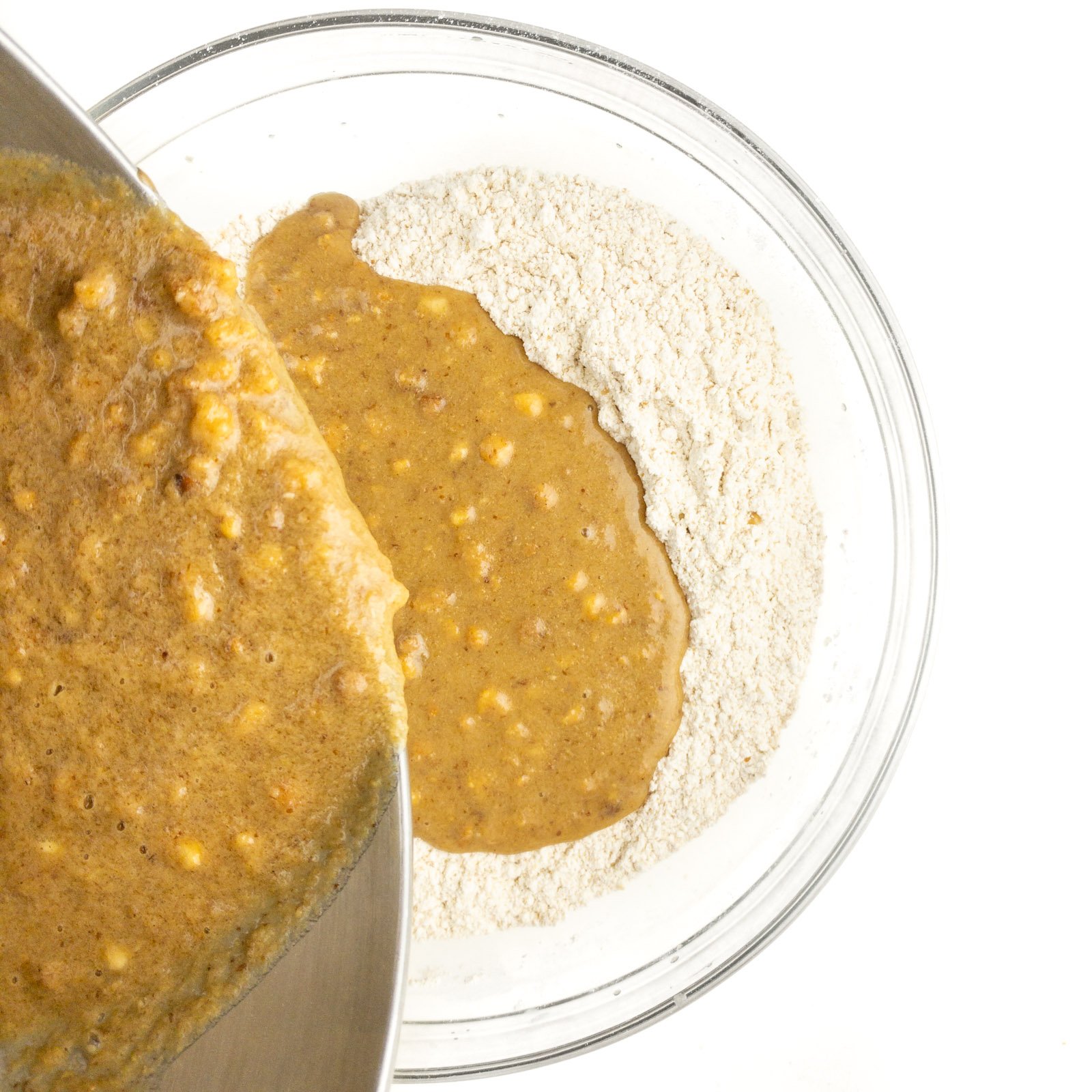 A bowl of wet ingredients are being poured into a bowl with a flour mixture.