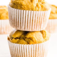 Two peanut butter muffins are stacked with more muffins behind them.