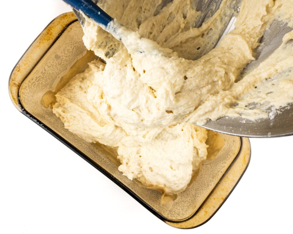 Batter is being poured into a loaf pan.