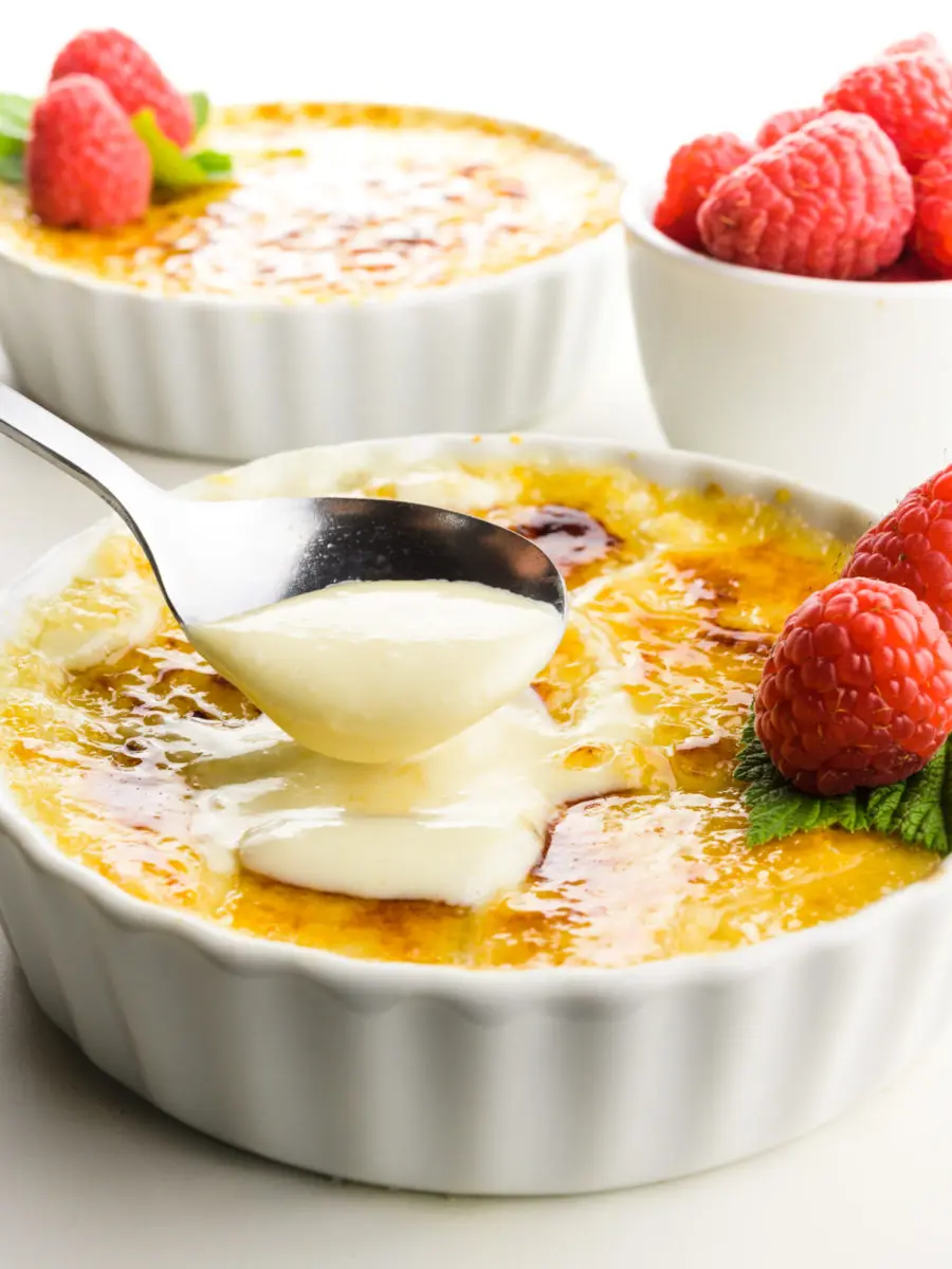 A spoon scoops out some cream from a serving dish of crème brûlée.