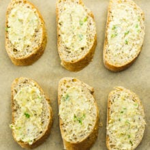 Looking down on several slices of buttered bread ready to go into the oven.