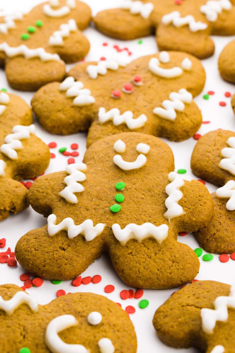 A close-up of a vegan gingerbread cookie next to several other decorated cookies.